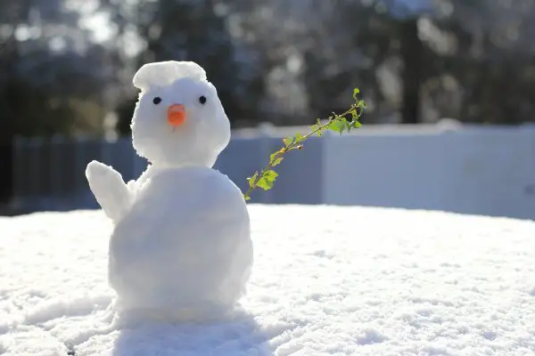 A white snowman outdoors on the snow.